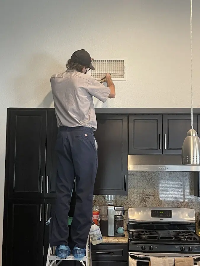 Technician inspecting an air vent during HVAC service in Rindge